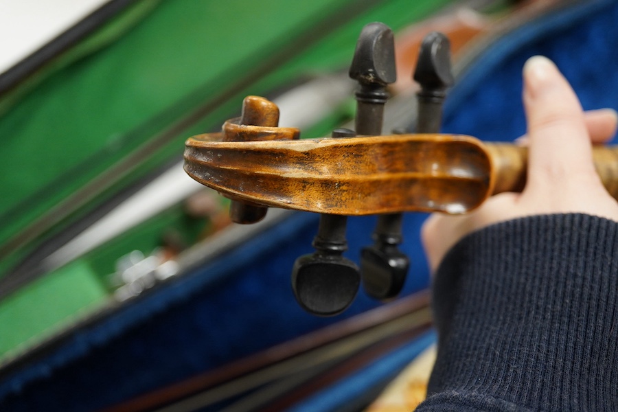 Four cased violins; an early 20th century violin, body 36cm, fitted with a microphone pick up taking a quarter inch jack plug, an early 20th century half size violin, body 32cm, and two student violins. Condition - poor